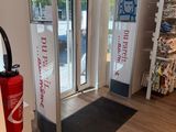 un magasin avec une grande porte vitrée et un paillasson noir au sol