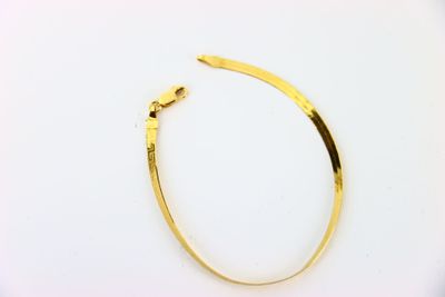 gros plan d'un bracelet en or sur une surface blanche