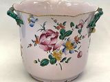 a pink vase with flowers on it on a white surface