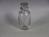 a small glass bottle with a silver lid on a white surface