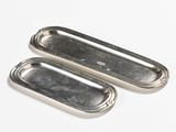 two silver metal trays sitting on top of a white surface