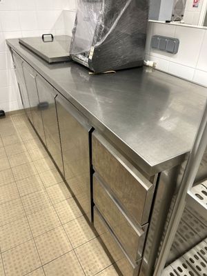 un plan de travail en acier inoxydable dans une cuisine professionnelle, sur lequel est posé un sac poubelle