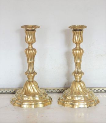 une paire de bougeoirs anciens en laiton posés sur une table en marbre
