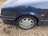 a picture of a blue car parked on a gravel lot