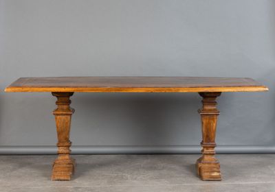 une vieille table en bois avec deux pieds tournés et un plateau en bois