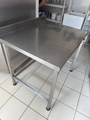 a stainless steel table in a kitchen with a refrigerator in the background