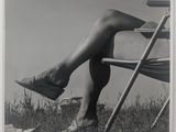 photographie en noir et blanc d'une femme assise sur une chaise, les jambes croisées
