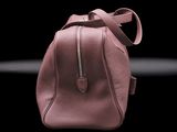 pink leather handbag on a black background with smoke coming out of it