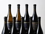 six bottles of wine are lined up on a wooden table