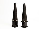 pair of black metal obelisks with gold accents on a white background