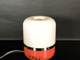 an orange and white lamp sitting on top of a black table