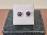 a pair of blue sapphire stud earrings sitting on top of a white cloth