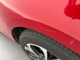 a close up of a red car with scratches on the side of it