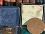 a gold medal sitting in a case next to a pile of books