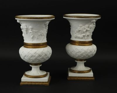 paire de vases blancs à bordure dorée, posés sur des socles