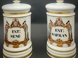 deux boîtes blanches et dorées sur lesquelles figurent les portraits d'un homme et d'une femme
