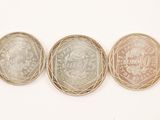 Trois pièces de monnaie britanniques différentes sont représentées en rangée sur une surface blanche.