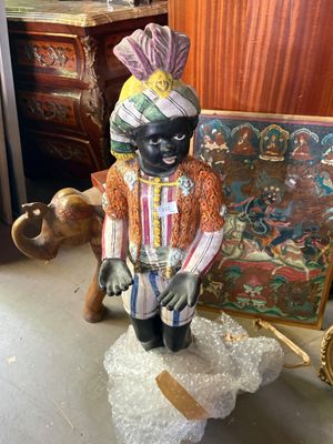 une figurine représentant un homme noir assis sur un rocher