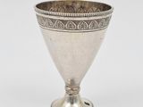 un gobelet ancien en argent posé sur une surface blanche, sur fond blanc