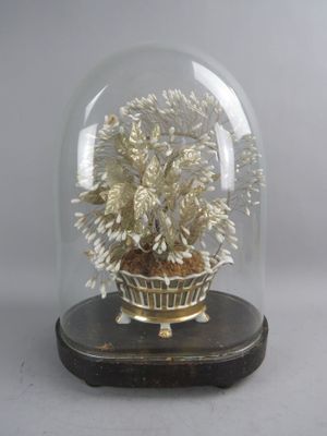 une cloche en verre contenant une plante, posée sur un socle en bois