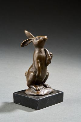 sculpture en bronze représentant un lapin, posée sur un socle en marbre, sur une surface grise