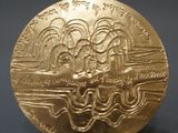 a close up of a gold coin on a stand on a gray surface