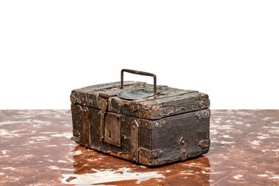 une vieille valise posée sur une table, sur fond blanc