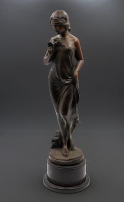une statue en bronze d'une femme tenant un oiseau sur un piédestal