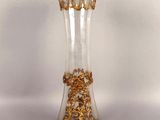 a glass vase with gold decoration on it on a white surface