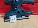 une ponceuse orbitale Bosch posée sur une table, avec une boîte rouge en arrière-plan