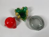 three glass objects on a white surface one is red and the other is green