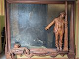 une statue représentant un homme debout devant un tableau