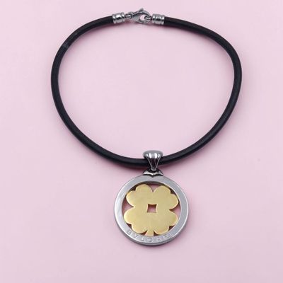 un pendentif en forme de fleur, en argent et en or, monté sur un cordon noir