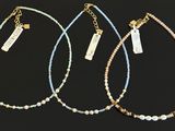three necklaces with gold and blue beads on a black background