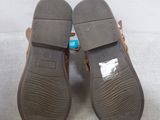 pair of women ' s brown sandals on a white surface with a bottle of toothpaste
