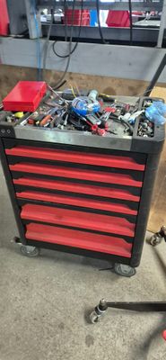 une boîte à outils rouge contenant des outils, dans un garage