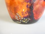 un vase coloré orné d'un papillon, posé sur une table