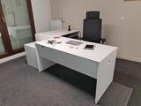 un bureau blanc avec une chaise noire et un ordinateur portable posé dessus