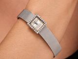 the woman is wearing a silver bracelet with a square watch on her wrist