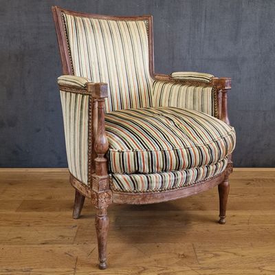 une vieille chaise dont l'assise est recouverte d'un tissu rayé