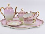 a pink and gold tea set on a tray