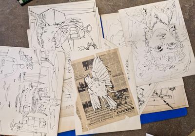une pile de dessins posés sur une table, à côté d'une paire de ciseaux et d'une paire de ciseaux