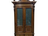 une armoire ancienne en bois, dotée de portes vitrées et de sculptures ouvragées