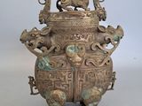 a large bronze vase with animals on it on a table