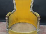 an old yellow chair sitting on top of a carpeted floor