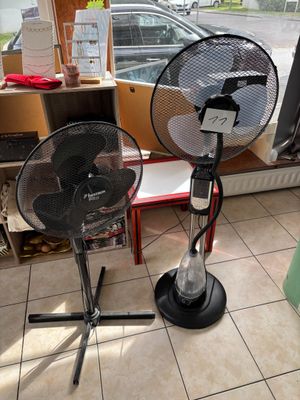 two fans that are sitting on the floor in front of a window