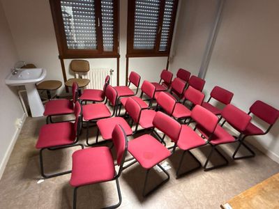 des rangées de chaises rouges dans une pièce équipée d'un lavabo et d'une fenêtre