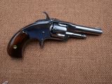a close up of a revolver with a wooden handle on a brown background