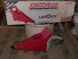 a red blower sitting on the floor in front of a box