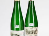 deux bouteilles de vin posées l'une à côté de l'autre sur une surface blanche